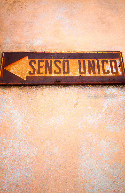 复古的意大利单向标志(“SENSO UNICO”)背靠粉红墙